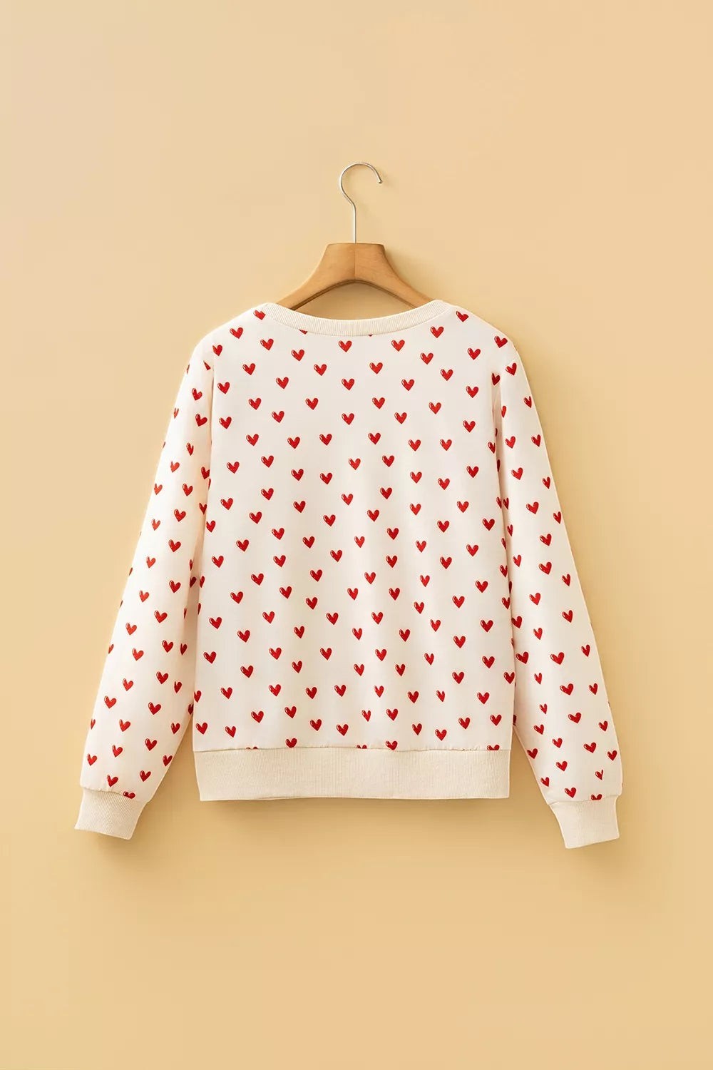 Health Hive cream long sleeve sweatshirt featuring a repeating red heart print, round neck, and ribbed trim.