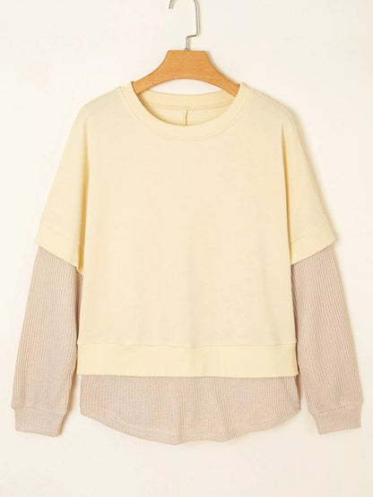 Health Hive cream and beige 2-in-1 faux two-piece patchwork sweatshirt with a round neck and waffle knit sleeves.
