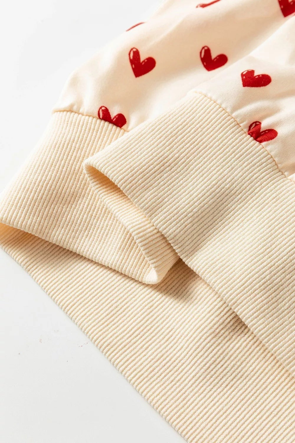 Health Hive cream sweatshirt with red heart print and ribbed cuffs made from a soft polyester blend fabric