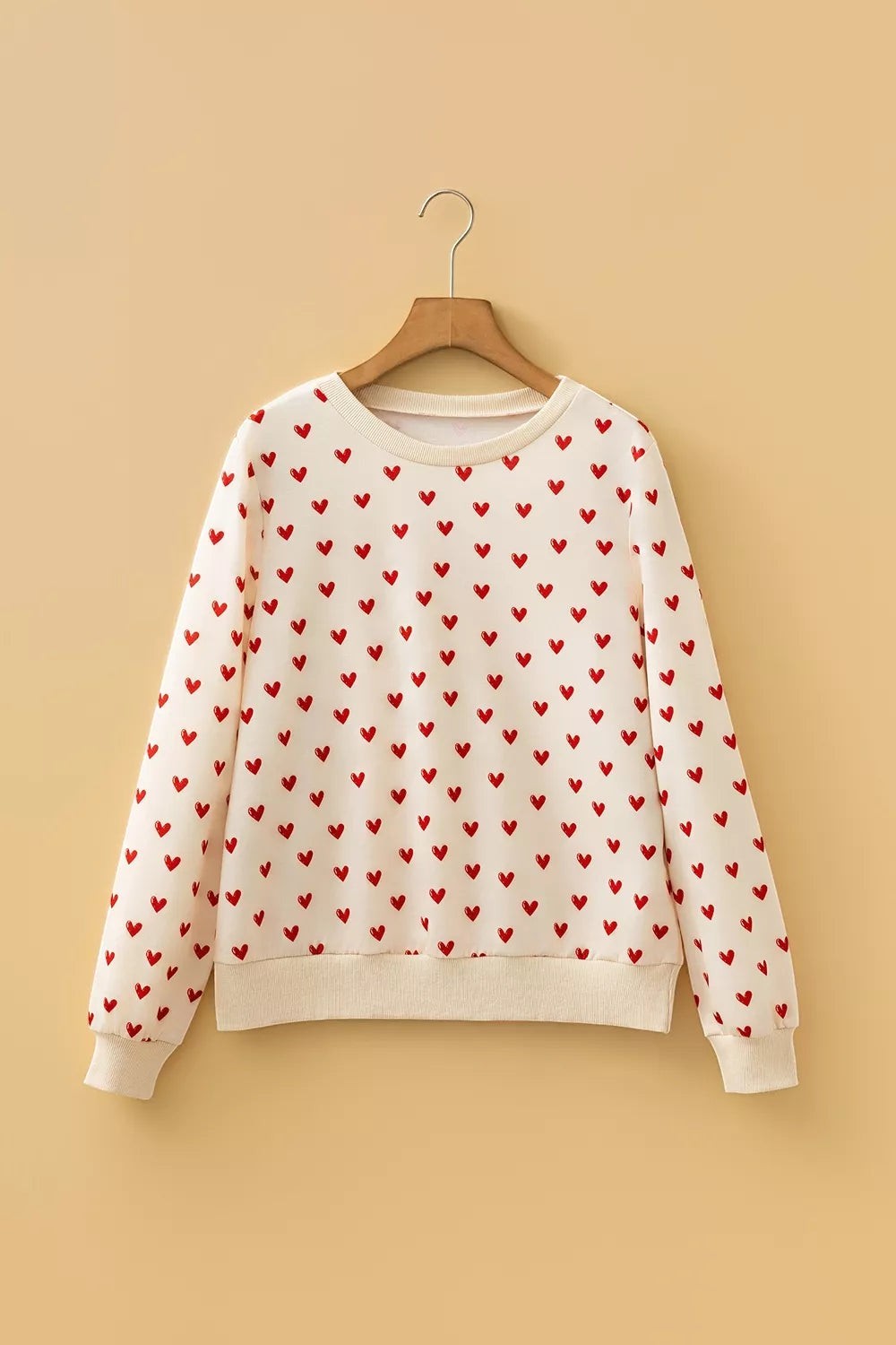 Health Hive cream long sleeve sweatshirt featuring a repeating red heart print, round neck, and ribbed cuffs.