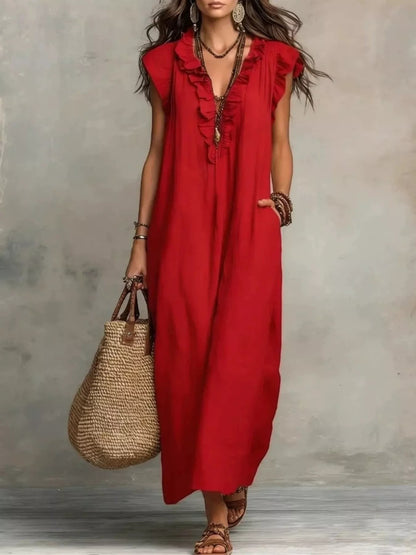 Health Hive red maxi dress with ruffled V-neck, cap sleeves, and side pockets, styled with a straw tote bag.